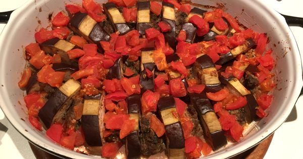 Turkse ovenschotel met tomaat, aubergine en gehakt op een houten plank