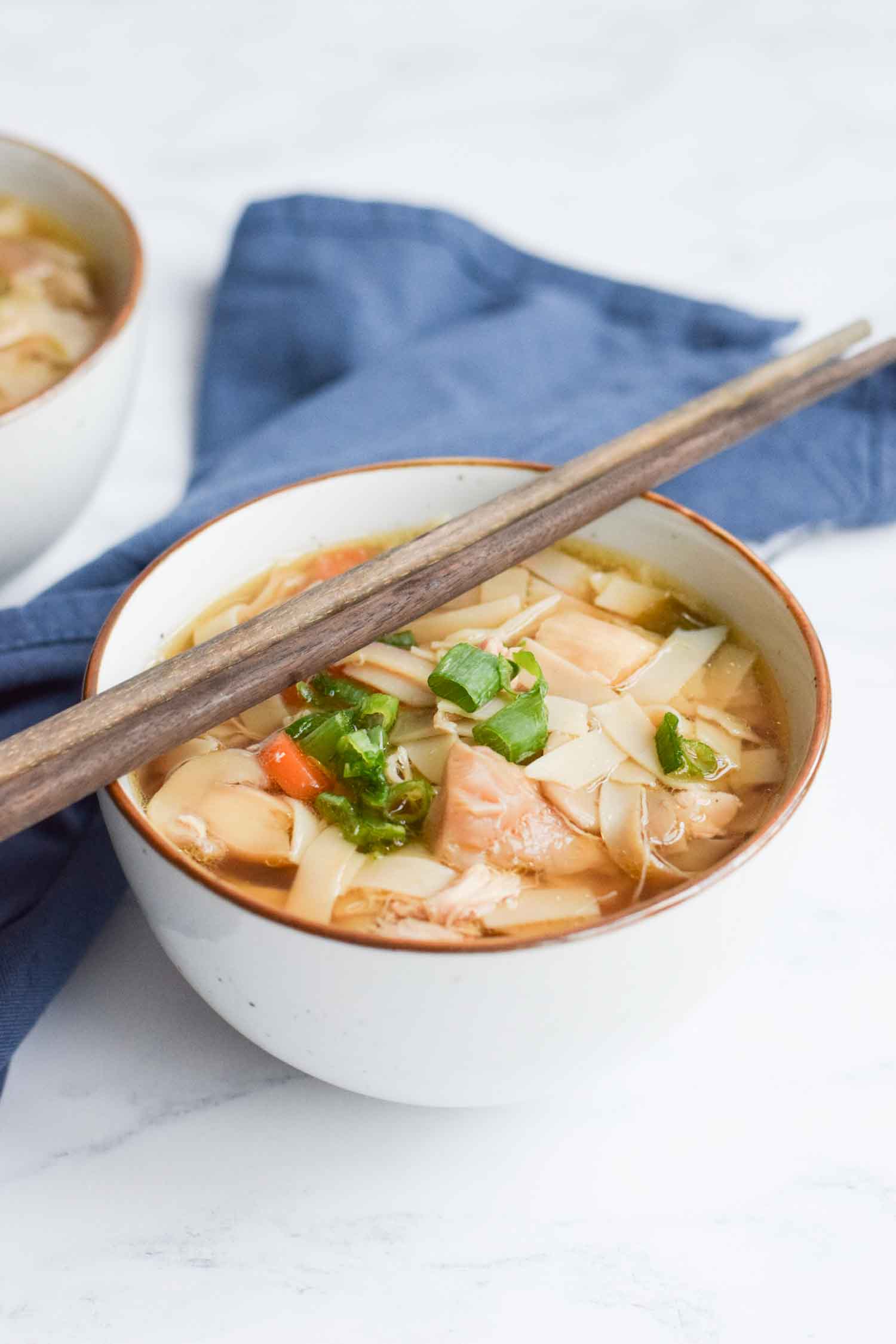 A bowl of low FODMAP chicken noodle soup with chopsticks