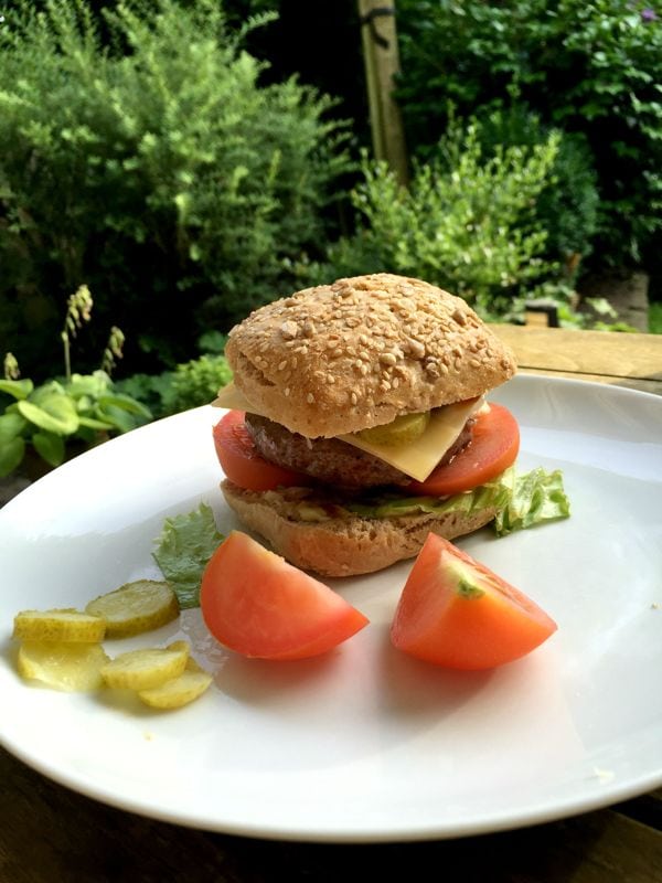 A low FODMAP burger on a bun with a garden in the background