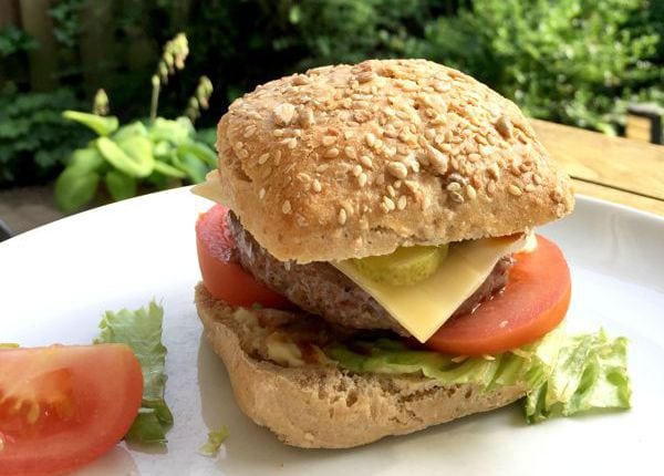 A low FODMAP burger on a bun with tomato, pickles and cheese