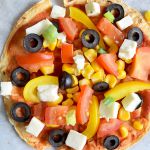 Een low FODMAP wrap pizza met tomaat, mais, olijven en feta