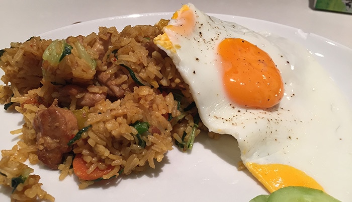 A plate of nasi goreng with a fried egg and cucumber