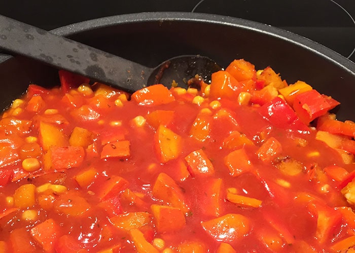 Vegetables with enchilada sauce in a pan