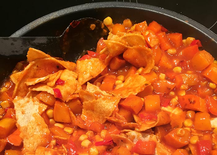 Vegetables with enchilada sauce and corn tortillas in a pan