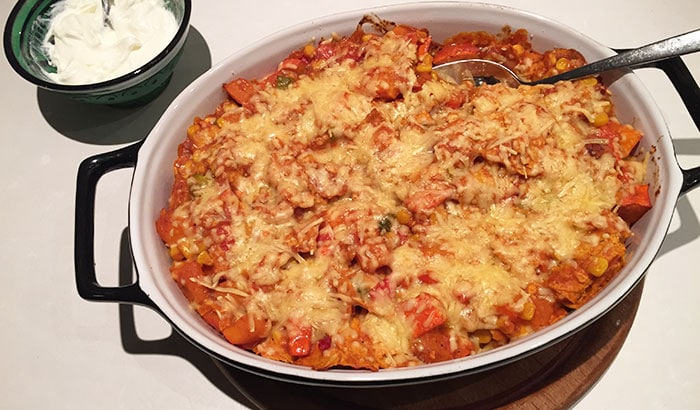 A low FODMAP Mexican casserole photographed from above with a bowl of creme fraiche next to it