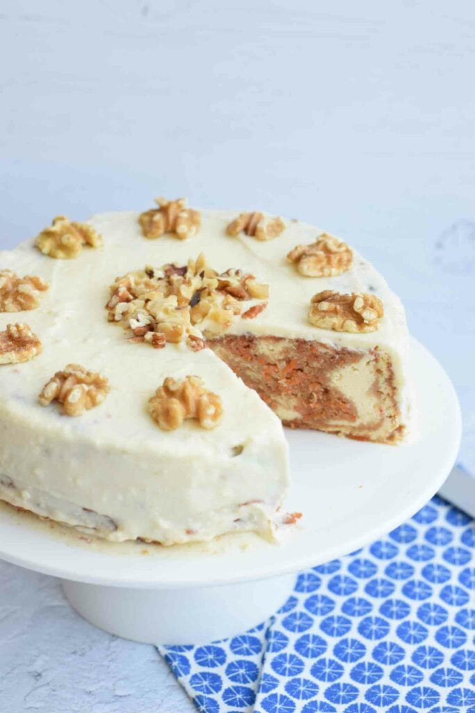 A carrot cake cheesecake with a piece out of it