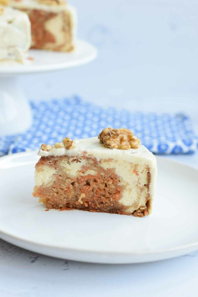 A piece of gluten-free carrot cake cheesecake with a walnut on top