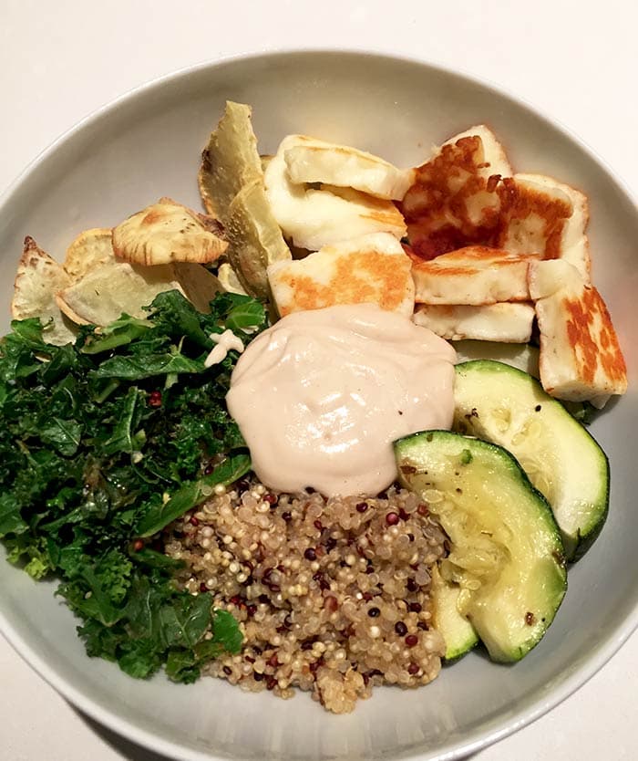 Vegetarische quinoa bowl met boerenkool en halloumi met tahin dressing gefotografeerd van bovenaf
