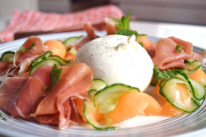 Melon salad with parma ham and burrata on a plate