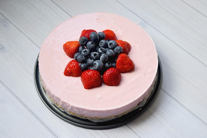 A healthy lactose-free cheesecake with strawberries and blueberries on top
