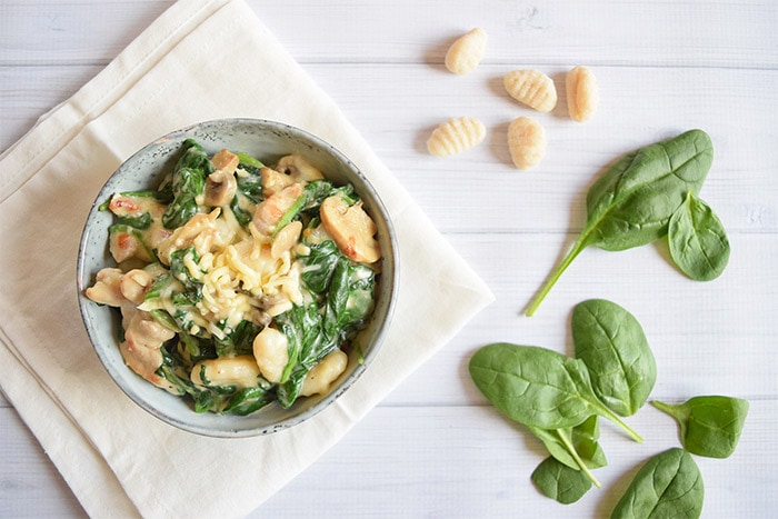 A bowl of low FODMAP chicken and spinach gnocchi photographed from above