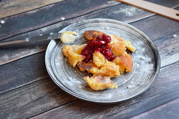 A plate with gluten-free kaiserschmarrn with jam and powdered sugar on toop