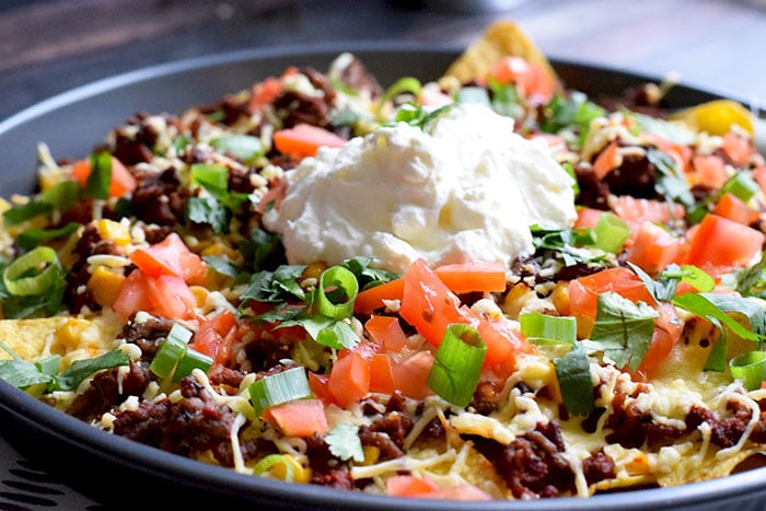 Low FODMAP nachos on a plate with creme fraiche on top