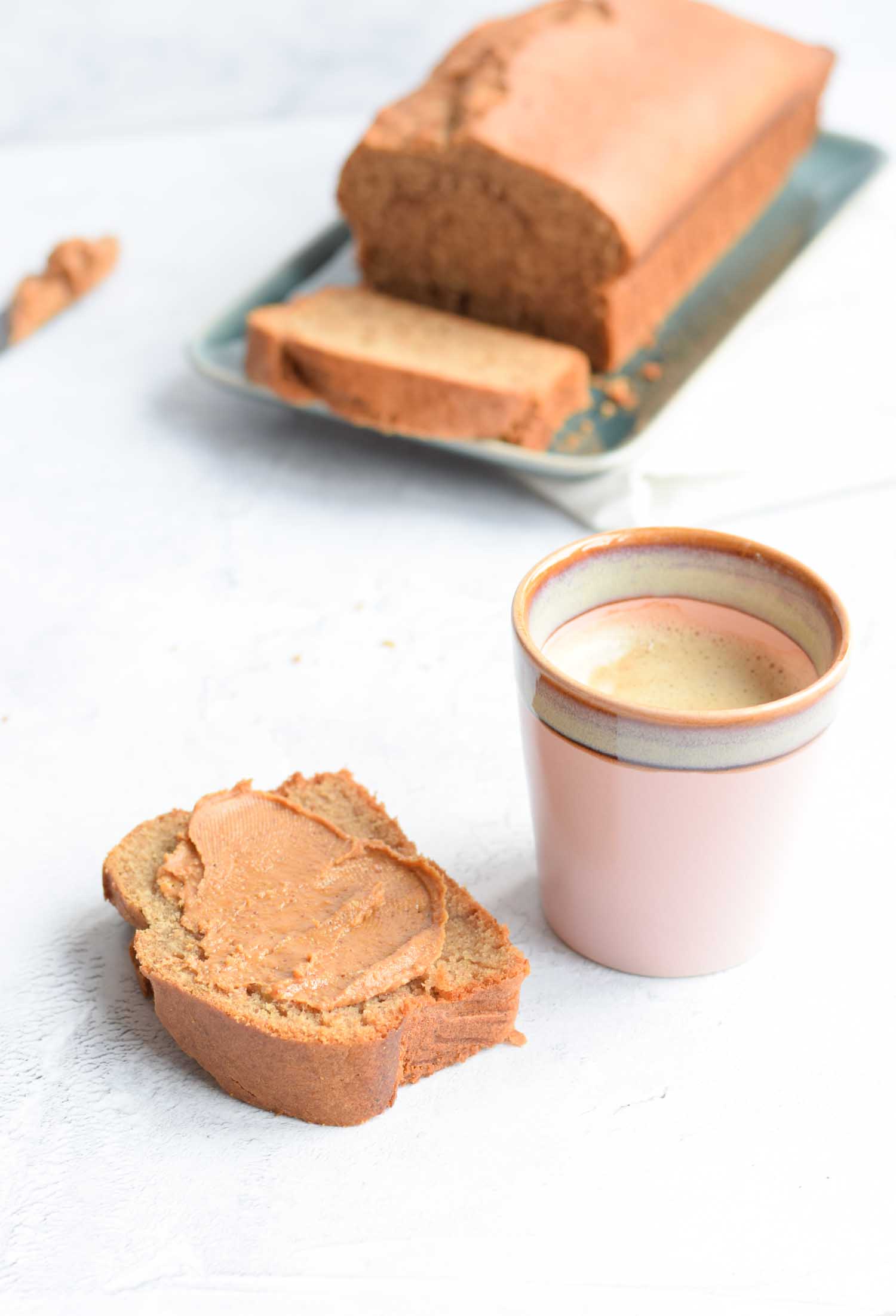 A slice of banana bread with a cup of coffee next to it