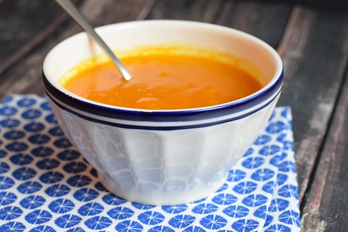 A white blue bowl with low FODMAP roasted pumpkin soup in it on a blue napkin