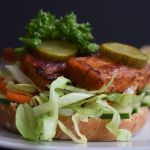 Een low FODMAP barbeque tempeh sandwich met augurk er bovenop