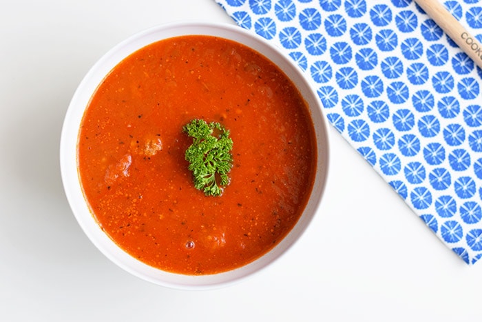 low FODMAP tomato soup with meatballs in a bowl with a blue napkin next to it