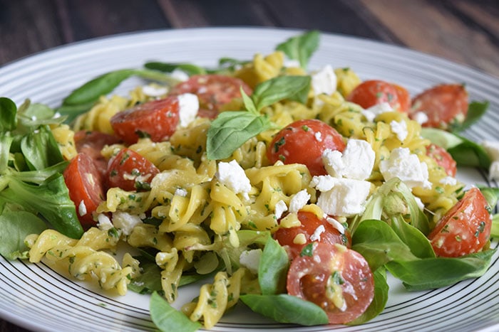 pasta pesto salade met tomaten en geitenkaas op een gestreept bord