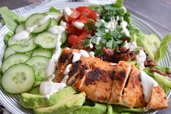 low FODMAP grilled chicken salad with yoghurt dressing on top