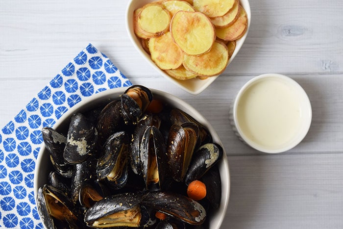 Low FODMAP mussels in a bowl with sauce and fried potatoes next to it
