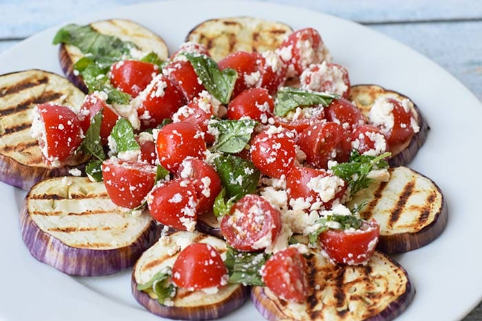 A plate with grilled eggplant with tomato and feta