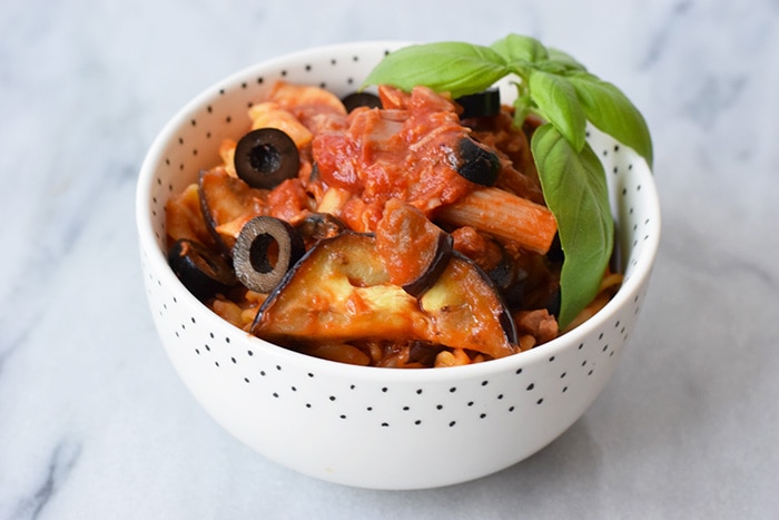 A bowl with low FODMAP pasta with tuna, grilled eggplant and olives with basil on top