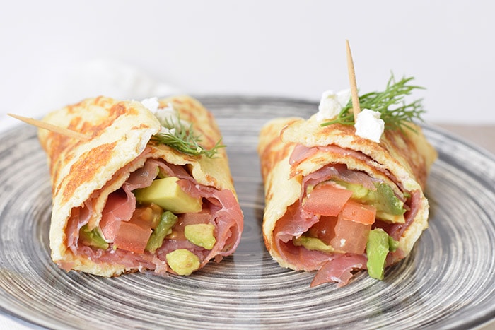 Low carb egg wrap filled with smoked meat, goat cheese, tomato and avocado