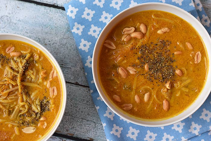 Two bowls of low FODMAP pumpkin noodle soup with peanuts photographed from above