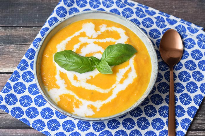 A bowl of low carrot soup with a spoon next to it