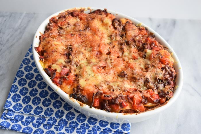 Low FODMAP lasagna bolognese in an oven dish on a blue napkin
