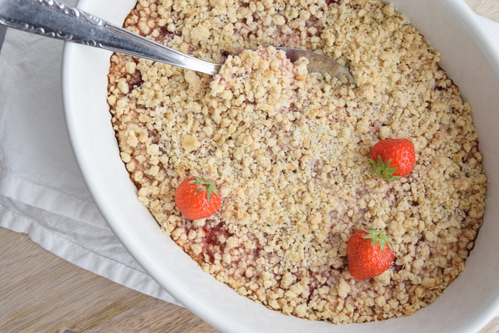 A dish with low FODMAP rhubarb crumble with strawberries on top