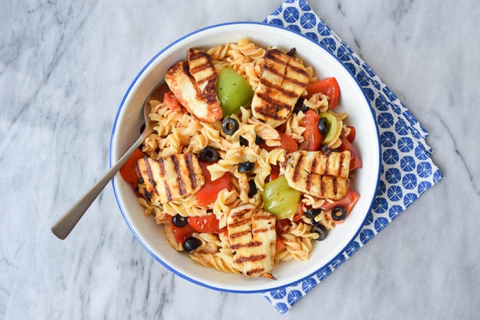 low FODMAP pasta salad with halloumi in a bowl with a blue napkin below