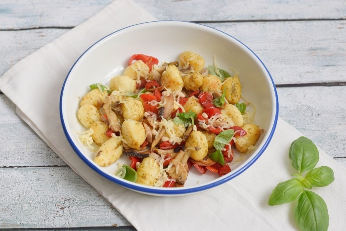 A bowl with low FODMAP fried gnocchi, pesto, bell pepper and mushrooms