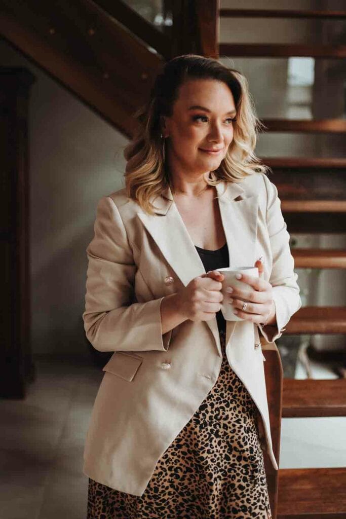 A woman in a blazer with a skirt holding a cup of coffee