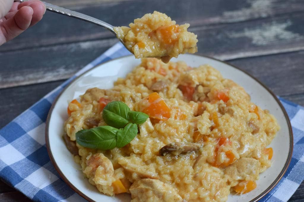 low fodmap chicken risotto on a plate and somebody taking a bite off of the plate with a fork