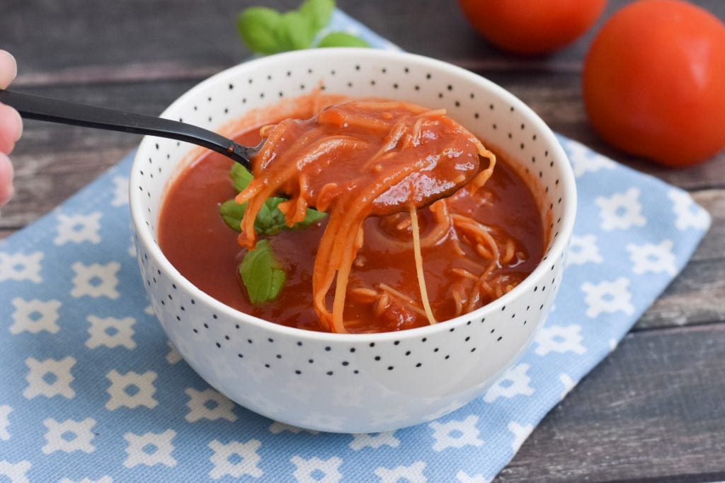 A spoon lifting some spice tomato soup out of a bowl