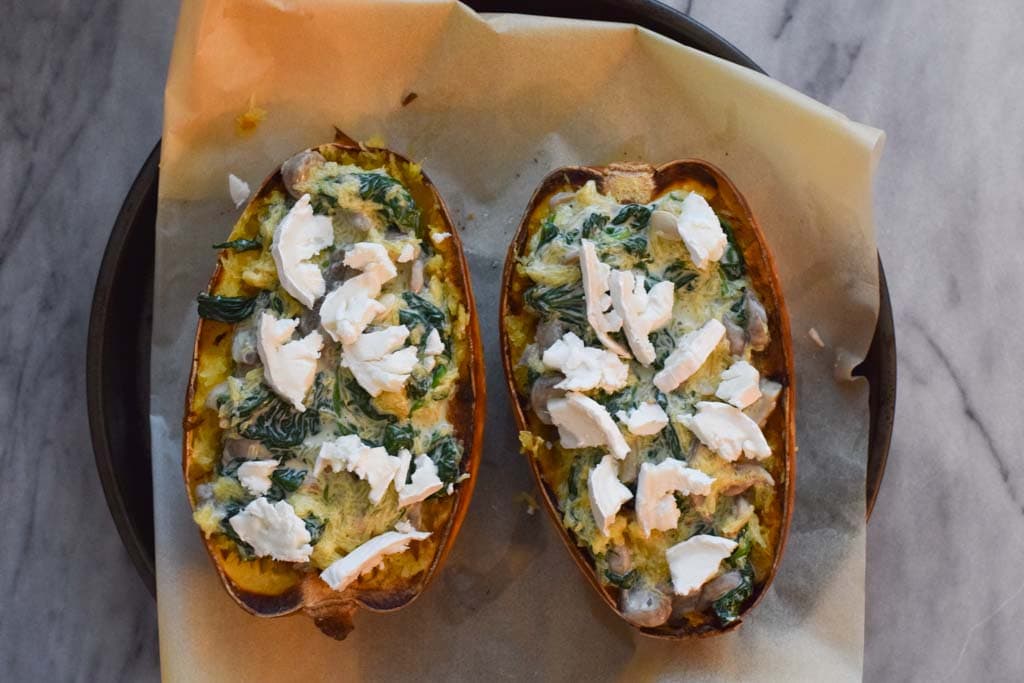 Two halves of low fodmap stuffed spaghetti squash with spinach and goat cheese