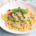 Low FODMAP creamy chicken pesto pasta with tomatoes and mushrooms on a plate