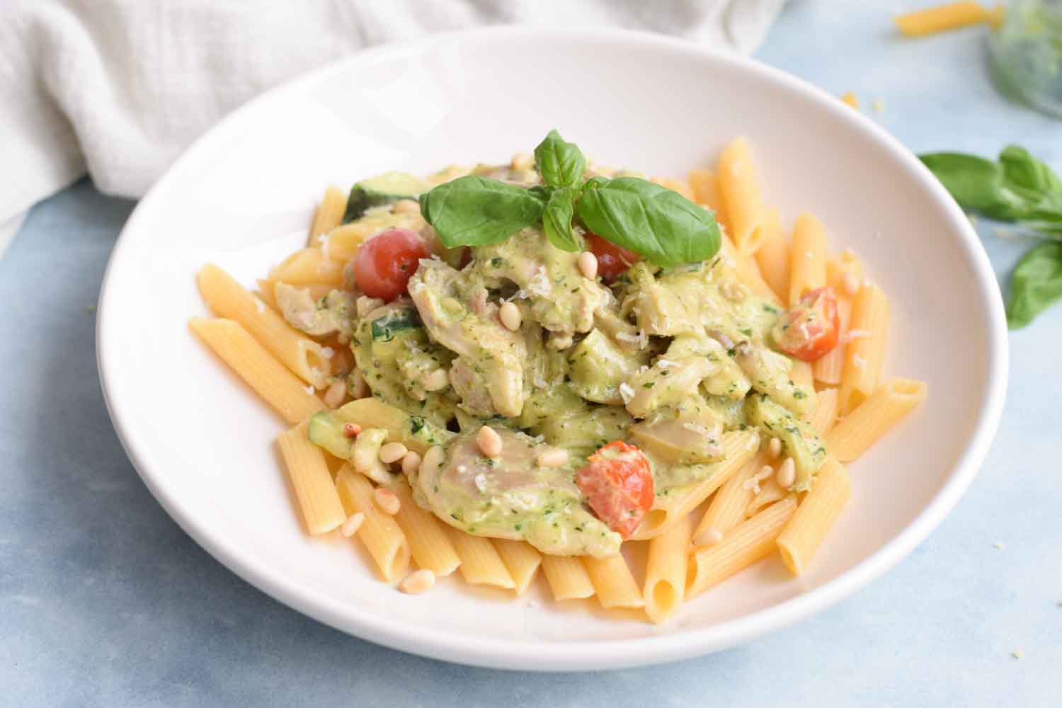 Low FODMAP creamy chicken pesto pasta with tomatoes and mushrooms on a plate