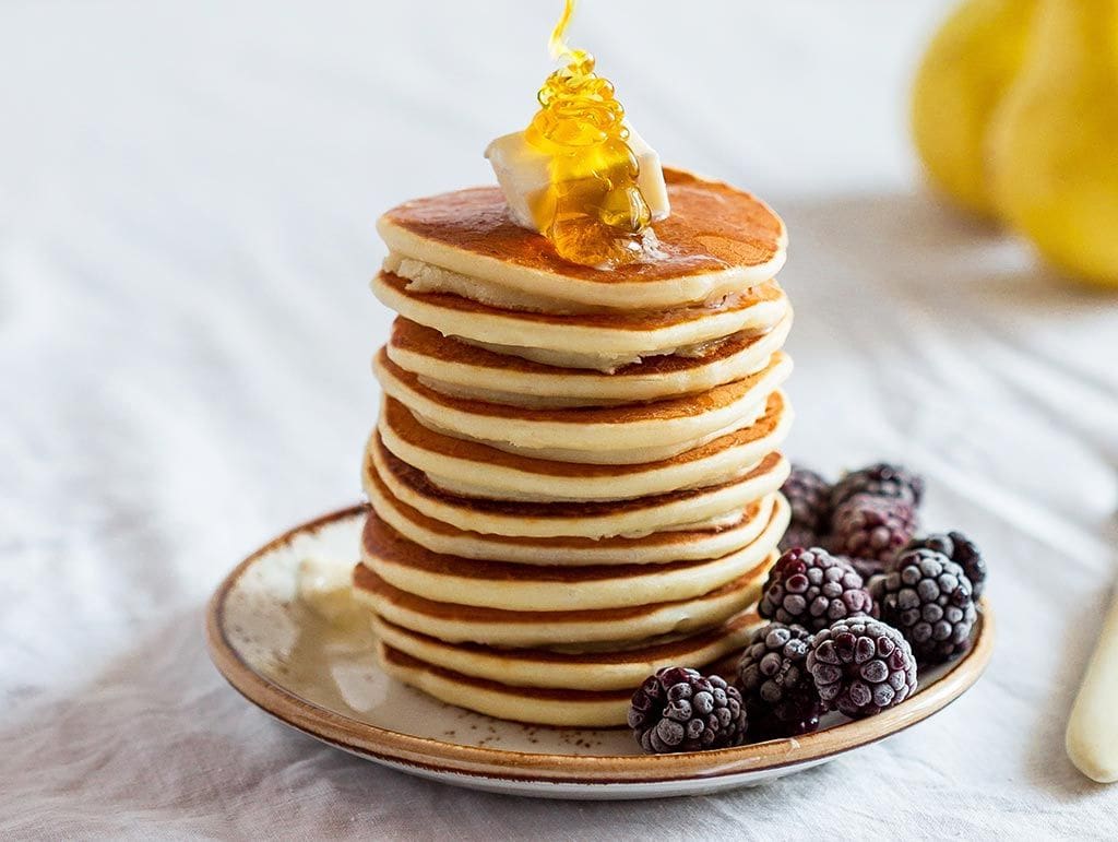 A stack of pancakes with berries next to it