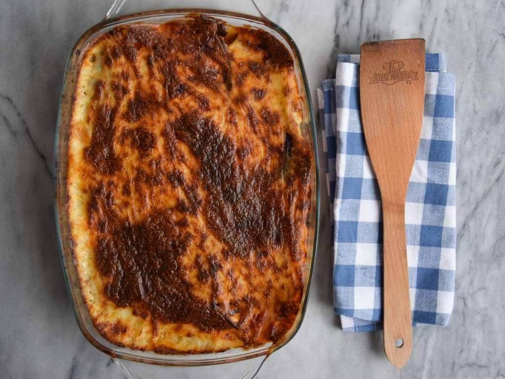 Low FODMAP moussaka with a spatula on a blue napkin next to it