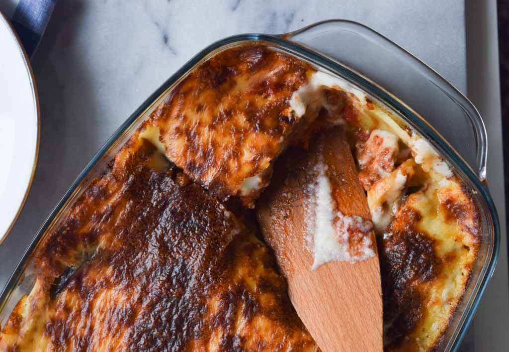 An oven dish with low FODMAP moussaka with a spatula in it taking out a piece