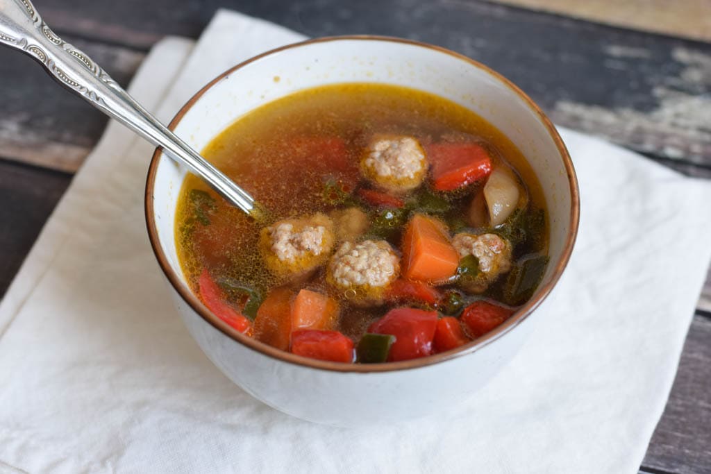 low fodmap vegetable soup with meatballs in a bowl with a spoon in it