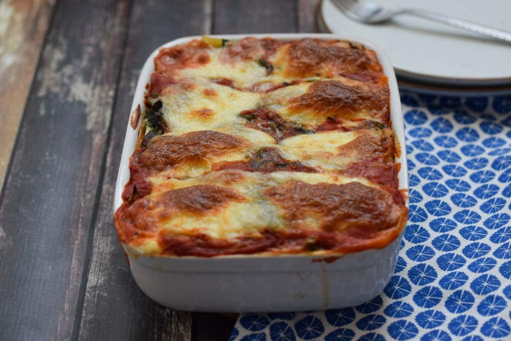 low fodmap vegetarische lasagne in een ovenschaal met een blauw servet ernaast