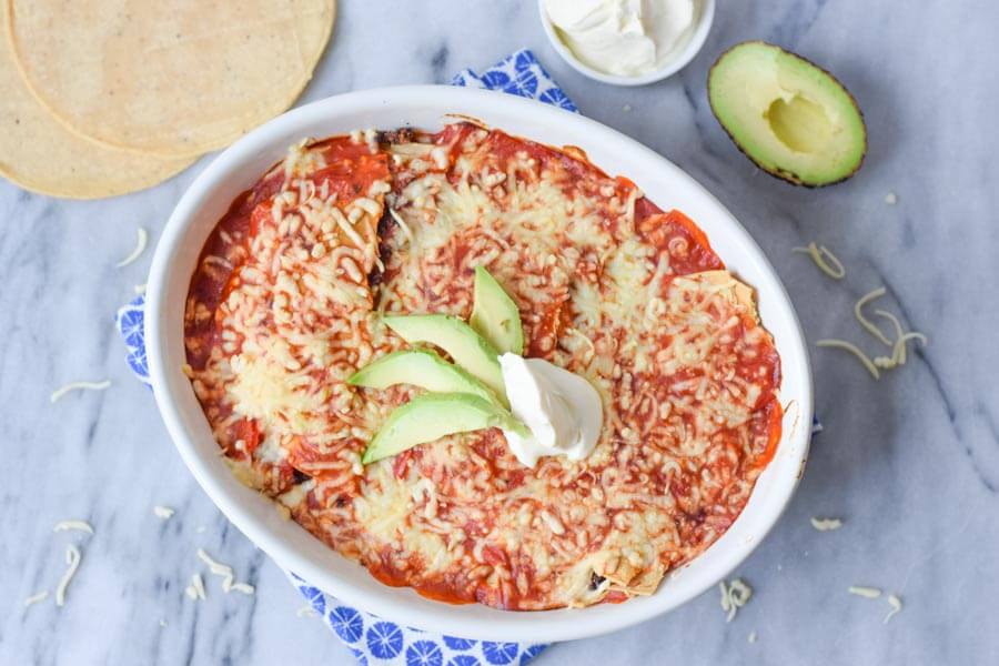 low fodmap enchiladas in a casserole dish with creme fraiche and avocado on top