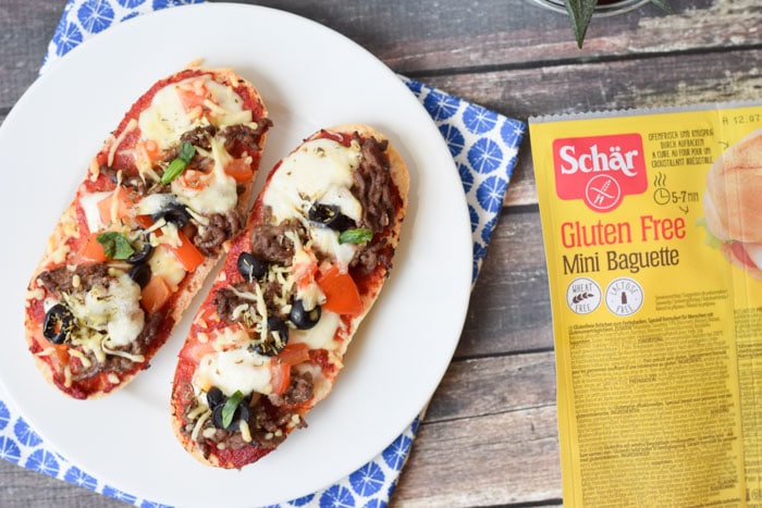 A low FODMAP pizza bread with a package of Schär gluten free mini baguette on the side
