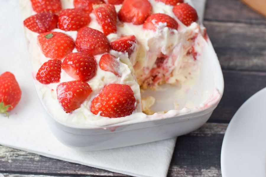 gluten-free tiramisu with strawberries in a dish with one piece taken out of it