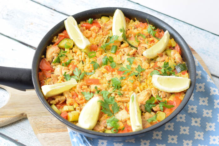 low FODMAP paella in a pan with lemon parts on top