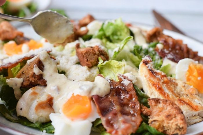 A low FODMAP caesar salad with caesar dressing over it