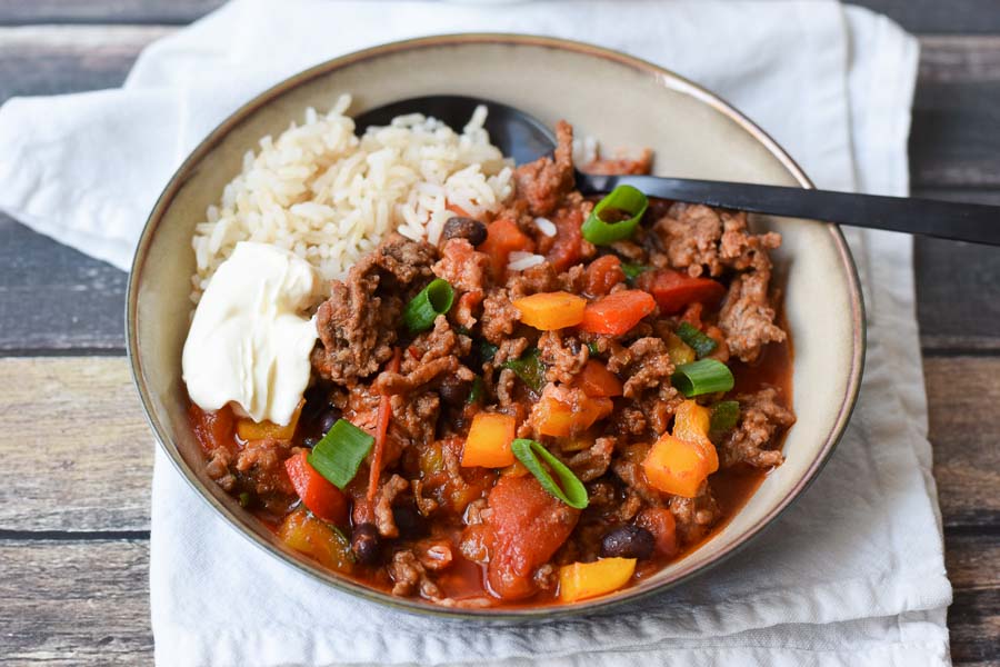 low fodmap chili con carne in a bowl with rice and creme fraiche
